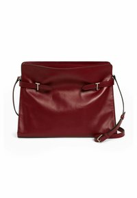 Bolso de mano de cuero burdeos con textura suave, que presenta un diseño plano, dos acentos de tiras y una correa de hombro desmontable.