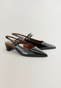 Musta läpinäkyvä nahkainen slingback-kenkä, jossa on terävä kärki, keskikorkea korko ja koristeelliset solkiremmit. Sujuva tekstuuri ja tyylikäs muotoilu.