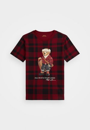 T-shirt à manches courtes à carreaux rouges et noirs avec une illustration d'ours vêtu d'une tenue en flanelle, avec un texte imprimé en dessous du graphique.