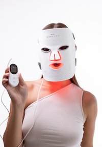 Vit LED ansiktsmask med perforerad design, utrustad med röda ljuselement; kopplad till en handhållen kontrollenhet.