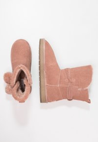 Růžové semišové kotníkové boty s texturovaným povrchem, umělou kožešinou na vnitřní straně a detailem mašle; plochá podrážka s protiskluzovými drážkami; zaoblená špička.