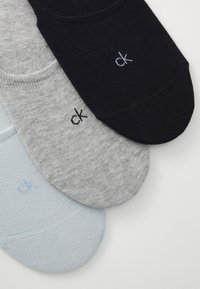 Σύνολο τριών ζευγαριών από κάλτσες μέχρι τον αστράγαλο: μαύρες, γκρι και ανοιχτό μπλε. Κατασκευασμένες από μαλακό ύφασμα με λεία υφή. Κάθε ζευγάρι διαθέτει το λογότυπο "ck".