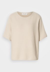 Beige kortermet topp laget av teksturert stoff, med rund hals og avslappet passform, med en etikett festet inni halsen.