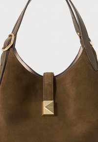 Sac à main en daim marron avec un design arrondi, présentant un accent doré et des poignées en cuir. Texture lisse et détails minimalistes.