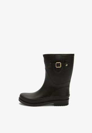Black rubber rain boot with a flat sole, round toe, textured upper, and a gold buckle accent on the side. Smooth, waterproof material.