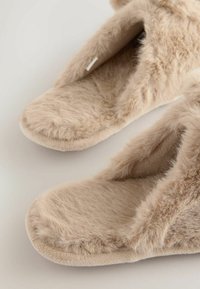 Faux fur slippers i lys beige, med en blød, tekstureret overdel og åben tå-design. Sålene er polstret for komfort.
