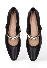 Chaussures en cuir noires avec un bout pointu, présentant un accent métallique courbé et un design de sangle découpée. Texture lisse avec une apparence classique.