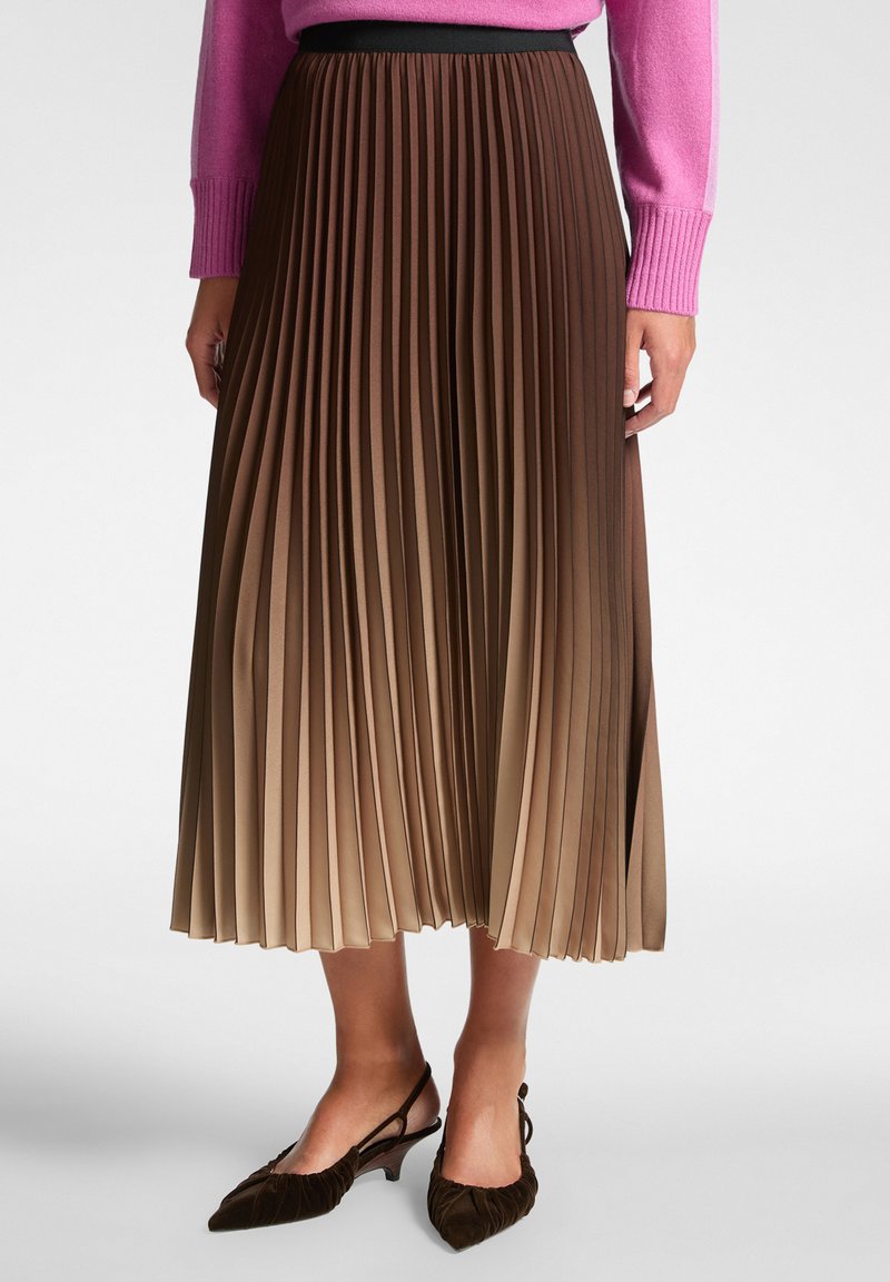 geplooide midi-rok in verloopkleuren van bruin, met een zwarte tailleband. Gestyled met bruine slingback schoenen. Textuurstof.