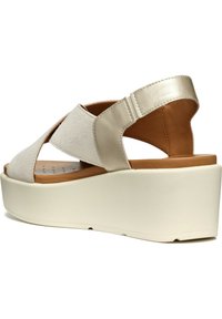 Sandali platform beige con tomaia testurizzata e dettagli in pelle liscia. Presentano una spessa suola bianca e un design a fascia incrociata che offre supporto.