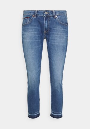 Blå jeans med slim pasform, klassisk fem-lomme-stil og knaplukning, let falmede med stikninger ved benenderne.