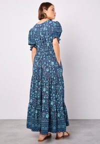 Blau-grünes Blumen-Maxikleid mit kurzen Puffärmeln, gerafftem Bund und gestuftem Saum, versehen mit seitlichen Taschen.