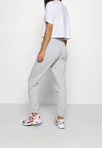 Szare spodnie dresowe ze zwężanymi nogawkami, elastycznym paskiem w talii, zestawione z wielokolorowymi sneakersami z mieszanką różowych, szarych i żółtych akcentów.