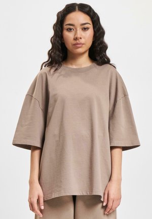 Bruine oversized katoenen t-shirt met korte mouwen, ronde halslijn en een ontspannen pasvorm; gladde textuur, eenvoudig ontwerp zonder patronen.