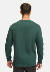 Langärmliges grünes Shirt mit geripptem Texture, Rundhalsausschnitt und geradem Schnitt. Verfügt über Bündchenärmel und ein glattes Rücken-Design.