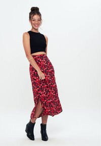 Sort ribbet crop top, rød blomster midi nederdel med sideslids, og sorte ankelstøvler. Lys blomsterprint på mørk baggrund.