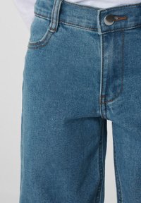 Modré džíny z denimu s vysokým pasem, klasickým designem s pěti kapsami, kontrastním oranžovým stehem a zapínáním na knoflík.