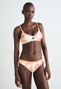 Blomsterbikini sett med lys oransje grunnfarge, rosa og blå mønstre, justerbare bånd på bunnen, og et utskåret detalj på toppen.