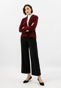 Burgundský cardigan s otevřeným předním dílem, kombinovaný s černými kalhotami s širokými nohavicemi a černými lodičkami. Měkká textura a uvolněný střih.