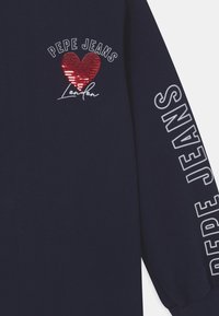 Granatowa koszula z długim rękawem, z napisem "Pepe Jeans London", czerwonym cekinowym sercem na piersi oraz napisem "Pepe Jeans" na rękawie.