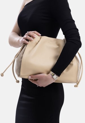 Beigefarbene Ledertasche mit strukturierter Oberfläche, Kordelzugverschluss und Zugbändern. Die Tasche hat ein geräumiges Design und ein kontrastierendes cremefarbenes Innenfutter.