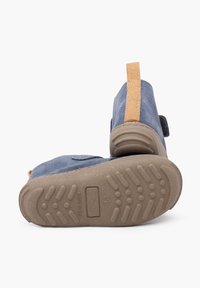 Calzature in suede blu con un accento beige sul tallone, suola in gomma e cinturino in velcro. Motivo del battistrada visibile sulla suola per una migliore aderenza.
