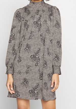 Blumenmusterkleid in Schwarz und Weiß, mit hohem Kragen, langen Ärmeln und lockerer Silhouette. Es hat zarte Punktmuster und geraffte Details.