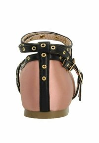Chaussures plates en or rose à finition mate, accents en cuir noir, bout rond, brides réglables à la cheville et détails en métal doré.