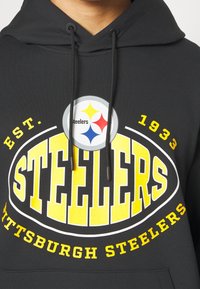 Sweat à capuche noir avec le logo des Pittsburgh Steelers, grand texte jaune "Steelers," et texte additionnel "Est. 1933" et "Pittsburgh Steelers" en jaune.