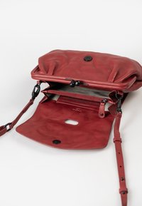 Borsa a mano in pelle rossa con finitura lucida, parte superiore plissettata, chiusura magnetica e tracolla regolabile. All'interno presenta un compartimento foderato e tasche.