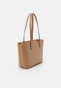 Ljusbrun väska i konstläder med två långa remmar, rektangulär form, rena linjer och minimalistisk hårdvara; slät yta utan synliga mönster.