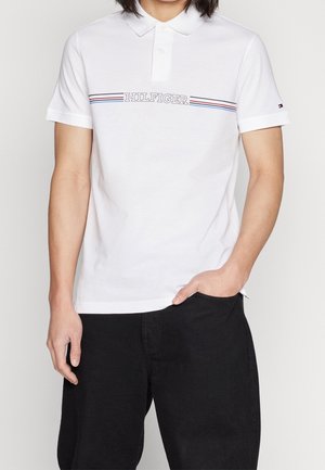 Biała koszulka polo wykonana z bawełny, z kołnierzykiem i krótkimi rękawami, z niebiesko-czerwonym poziomym paskiem i napisem „HILFIGER” na piersi.