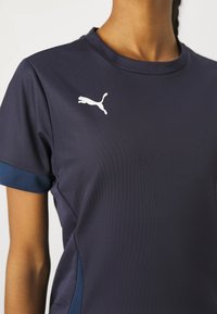Puma sports t-shirt i marineblå, med åndbare meshærmer, en rund halsudskæring og et hvidt logo på brystet. Glat tekstur.