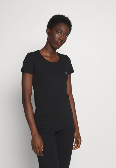 T-shirt en coton noir avec un col rond et des manches courtes. Petit logo sur la poitrine gauche. Design ajusté.