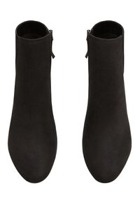 Une paire de bottines noires en suède avec des zips sur le côté, des bouts ronds et une texture lisse, vues de dessus sur un fond blanc.