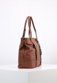 Bruine leren tote bag met een gestructureerde vorm, voorzien van twee lange handvatten en een rits afsluiting. Opvallend door zijn gladde textuur en minimalistisch ontwerp.