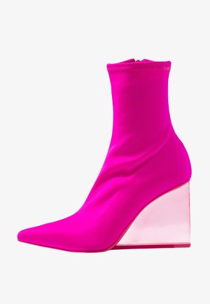 Pink stof ankelstøvle med spids tå og gennemsigtig kilehæl. Glat tekstur, tætsiddende design og syningdetaljer øverst.