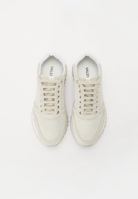 Beige sneakers met een mesh bovenwerk, tonale veters en rubberen zool. Perforaties aan de zijkanten, logo gedrukt aan de binnenkant.