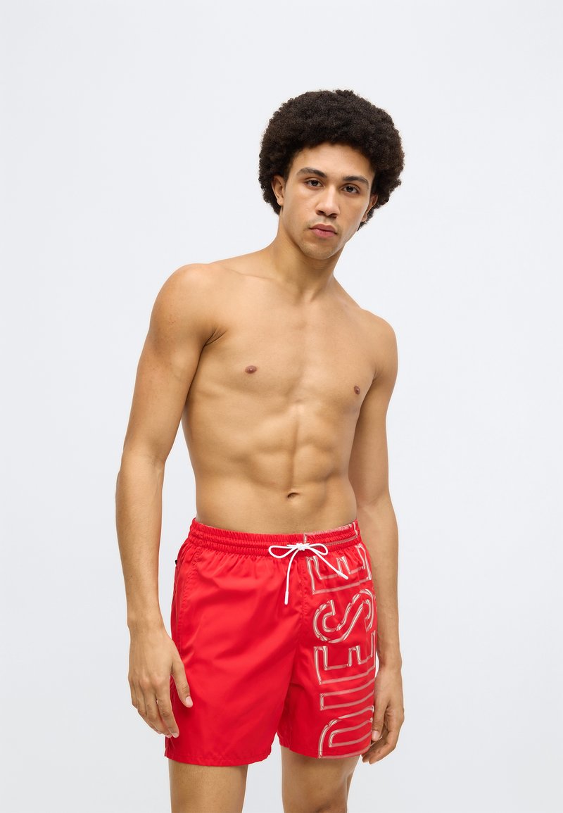 Röda badshorts med en glansig finish, med vit logotyptryck på sidan, resårmidja med dragsko och avslappnad passform.