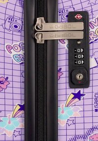 Valigia rigida con uno sfondo lavanda, decorata con motivi floreali e a stelle, dotata di doppie cerniere argento e di una serratura combinata.