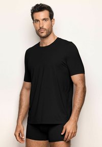 T-shirt noir à manches courtes en tissu lisse et léger, avec un col rond et une coupe décontractée, accompagné de boxers noirs.
