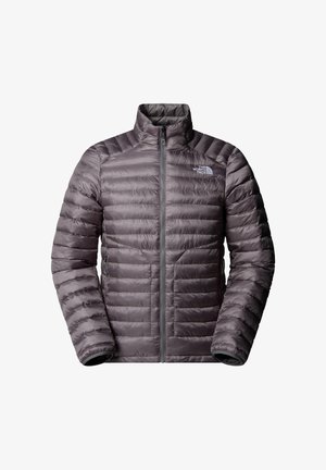 Chaqueta aislante gris con un cuello alto, que presenta costuras horizontales, un cierre frontal completo y bolsillos laterales. El logo de la marca es visible en el pecho.