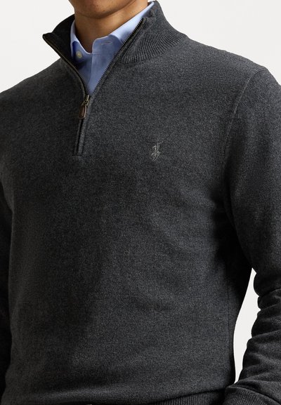Grijze zip-up trui met geribbelde kraag en manchetten, gemaakt van zacht materiaal, met een klein geborduurd logo op de bovenste linker borst.