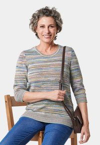 Mehrfarbiger gestreifter Strickpullover mit Dreiviertelärmeln, rundem Ausschnitt und strukturiertem Saum, kombiniert mit blauen Jeans und einer braunen Umhängetasche.