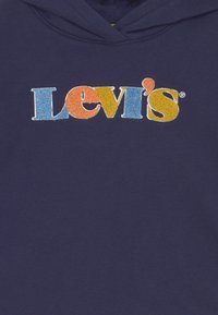 Marineblå hoodie med en flerfärgad texturerad Levi's-logga broderad på bröstet i blå, orange och gula bokstäver.