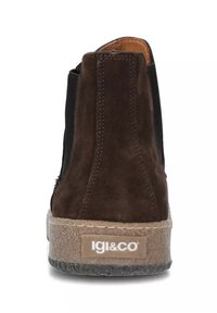 Stivale alla caviglia in suede marrone con un pannello in tessuto nero, suola texturizzata e accento del logo chiaro sul retro. Punta rotonda e design slip-on.