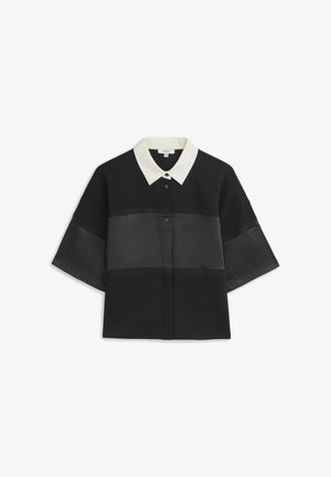 Chemise noire à manches courtes avec col blanc et panneaux transparents horizontaux sur la poitrine et les manches.