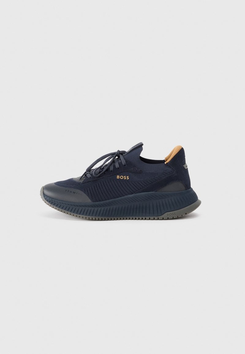 Baskets BOSS bleu marine avec empeigne en maille texturée, fermeture à lacets, semelle épaisse crantée et languette beige au talon, vues de profil sur un fond uni.