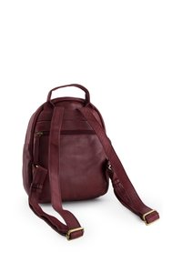 Burgundy leather backpack with a rounded shape, adjustable straps, a top handle, and a zippered pocket on the back. Textured surface detailing.