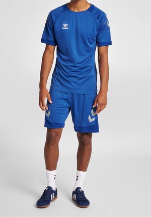 T-shirt de sport bleu et shorts en tissu respirant, avec un logo, des motifs contrastés et des accents gris sur les shorts.