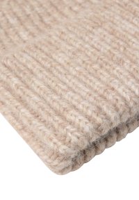 Beige strikket uldtekstil med ribbet mønster, blød tekstur og let fuzzy finish. Kanterne er pænt afsluttet med en subtil rund form.